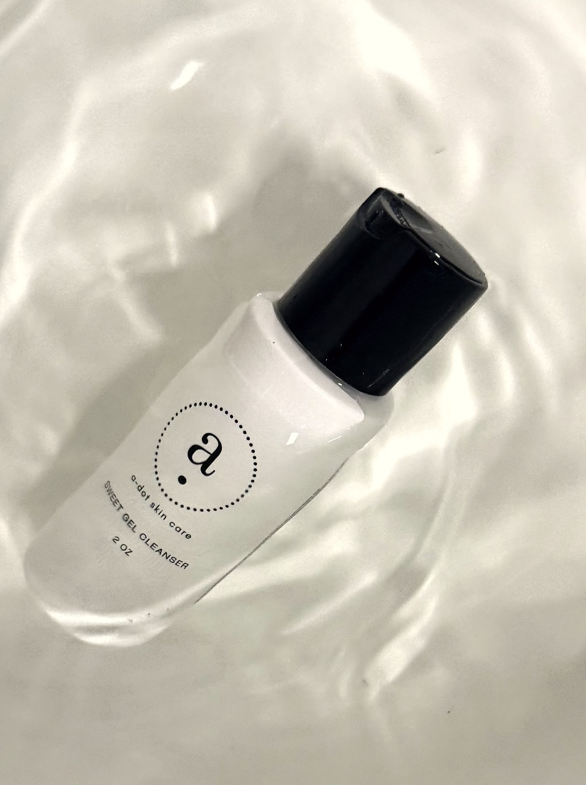 An a.dot skin care bottle resting in water